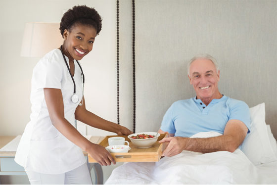 nurse assisting senior with breakfast